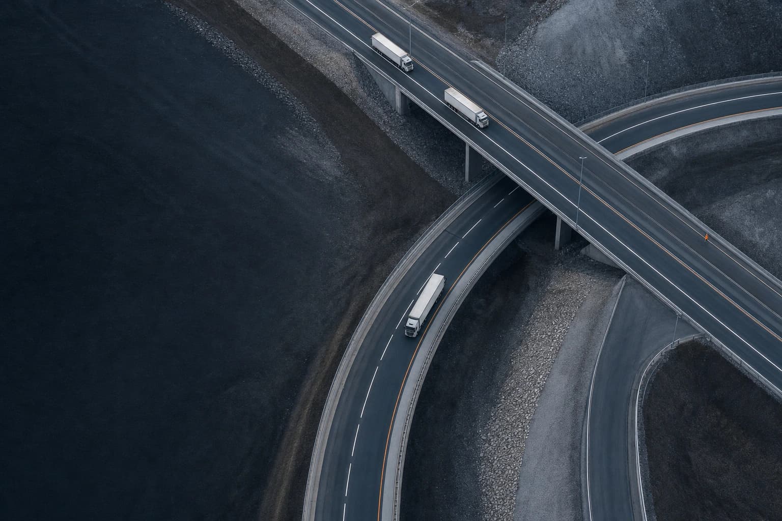 Three freight trucks moving through a layered highway interchange